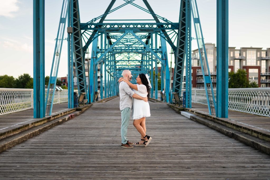 Engaged couple posing on the Chattanooga walking bridge facing each other