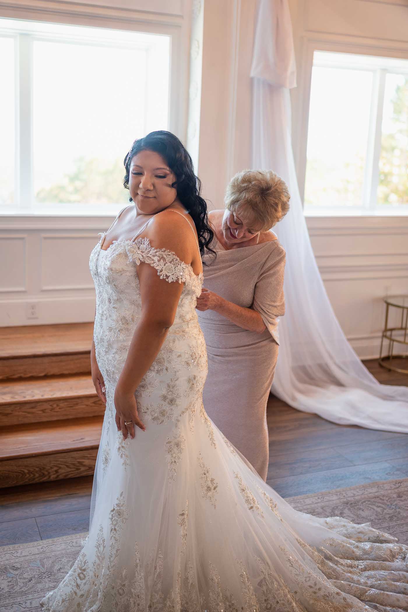 mom helping bride zip up her dress