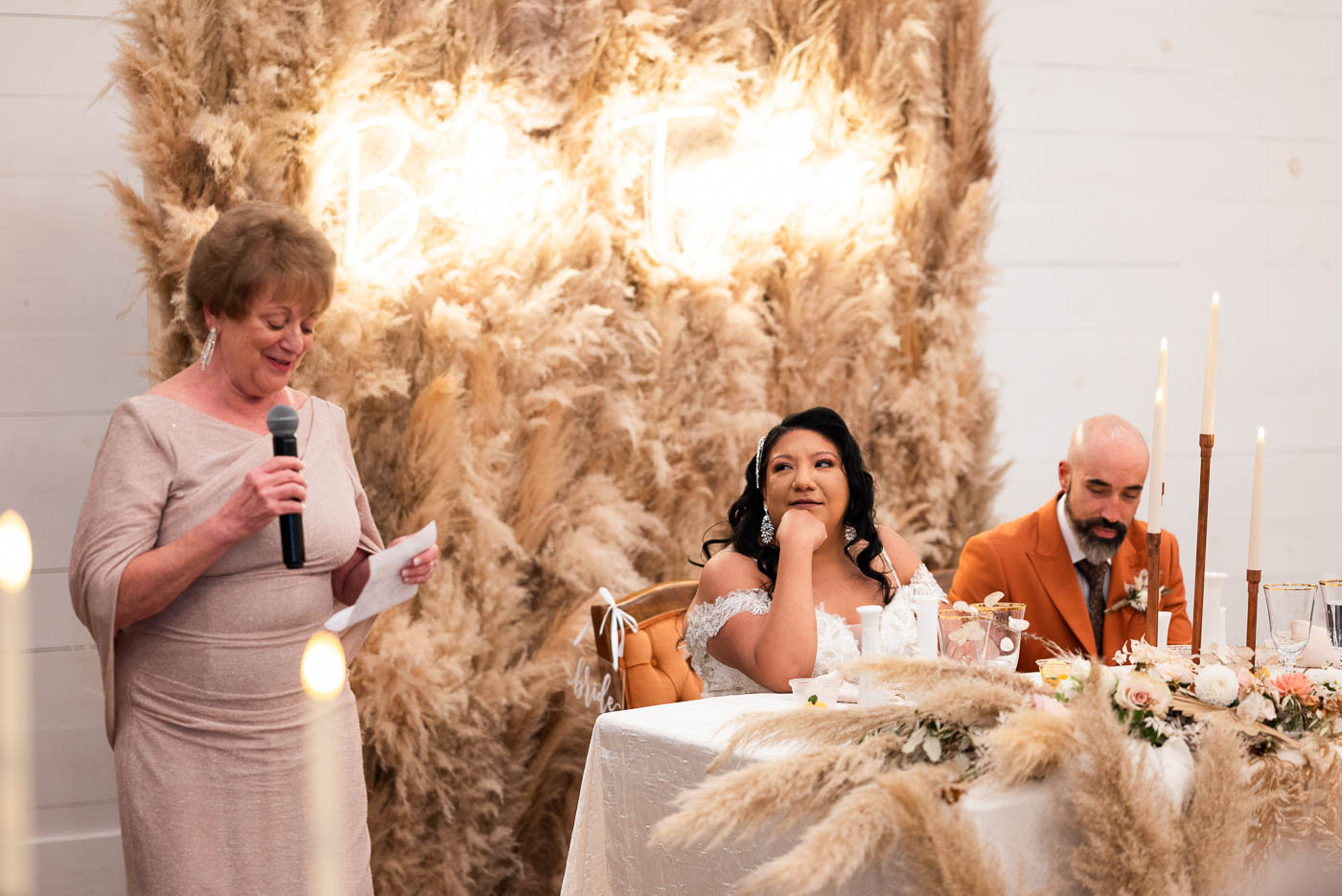 Bride smiling at her mother giving a speech